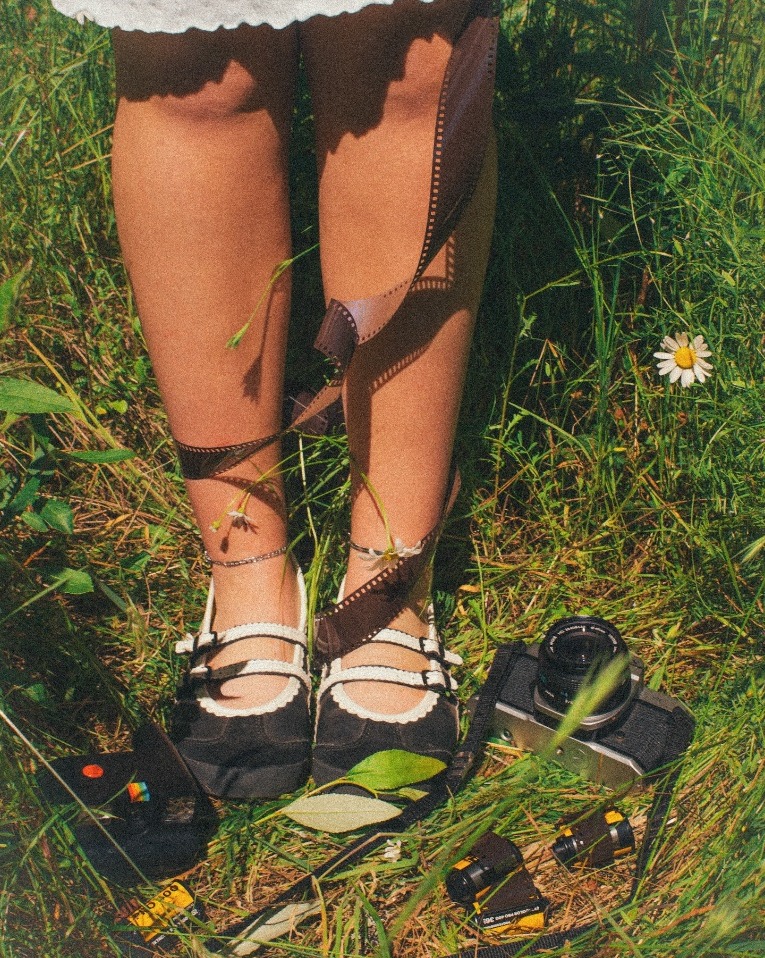 Carly's shoes, film camera and film strip in the daisies